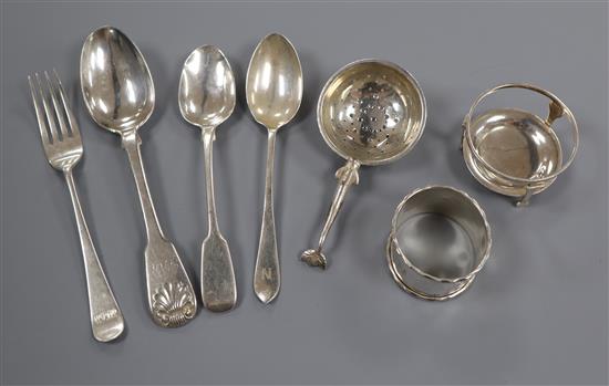 Four assorted silver teaspoons, a silver tea strainer on stand and a silver napkin ring.